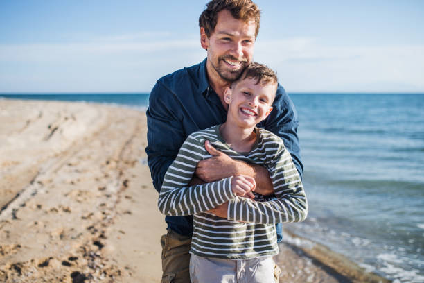 istock Father with small son on a walk outdoors on beach, having fun. 1153420592