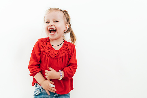 Cheerful laughing little girl in red blouse on the white background.