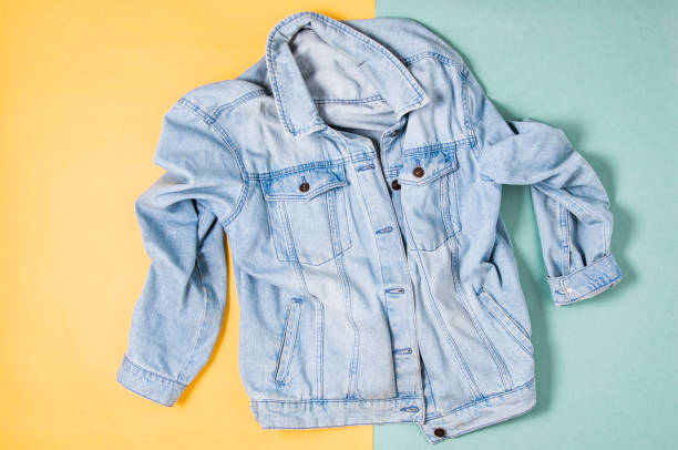 istock Blue denim jacket on yellow green background. Flat lay and top view 1153425691