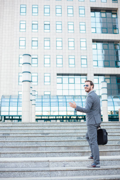 若いビジネスマンは、彼の肩の上に見て、オフィスビルの前で階段を登ります - staircase walking office steps ストックフォトと画像