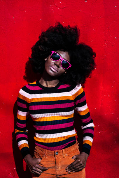 istock African woman standing hands in pockets on red background 1153427563