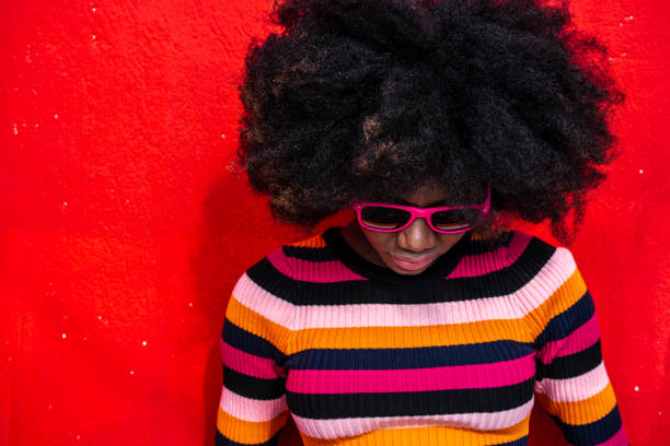istock African woman on red background, looking down 1153427565