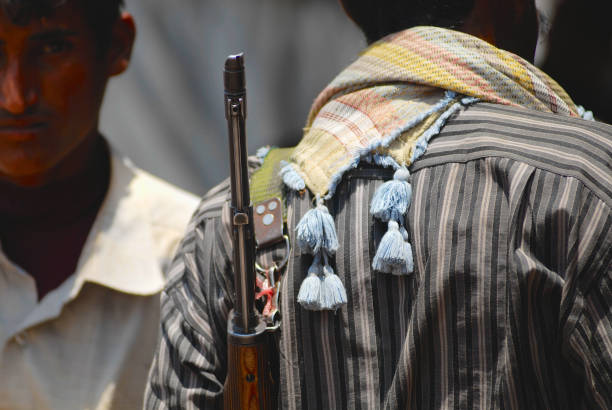Yemeni man holds a rifle on his shoulder at the street in Aden, Yemen. Aden, Yemen - September 14, 2006: Unidentified Yemeni man holds a rifle on his shoulder at the street in Aden, Yemen. militant groups stock pictures, royalty-free photos & images
