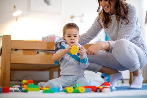 istock Little boy playing on the floor, mother dressing him 1153431749