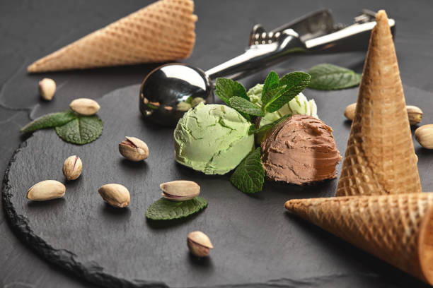 istock Gourmet chocolate and pistachio ice cream served on a stone slate over a black background. 1153436310