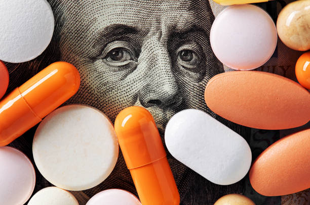 Money and healthcare policy concept. Colorful medical pills cover Benjamin Franklin's face on one hundred american dollar bill. Macro top down view. Capitalism and healthcare policy concept. Colorful medical pills cover Benjamin Franklin's face on one hundred american dollar bill. Macro top down view. Trafficking stock pictures, royalty-free photos & images