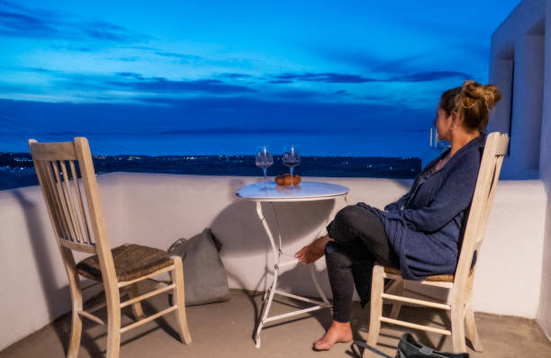 istock Alone woman sits on balcony at dusk with blue sky 1153438466