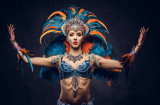 Studio portrait of a sexy female in a colorful sumptuous carnival feather suit. Isolated on a dark background. stock photo