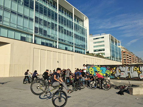 Buenos Aires, Argentina - June 2, 2019: Group of young boys hanging out together with their bikes riding bikes and showing off their skills in Puerto Madero neighborhood. This gatherings are already customary and they hold them every sunday