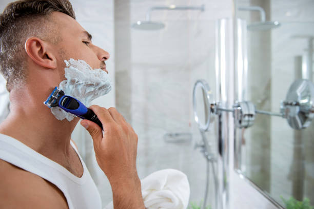istock Concentrated man shaving his face and looking at the mirror 1153440690