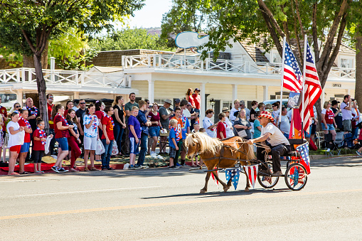 Kanab, UT, USA - July 4, 2018: A very patriotic pony cart races past 4th of July parade spectators.