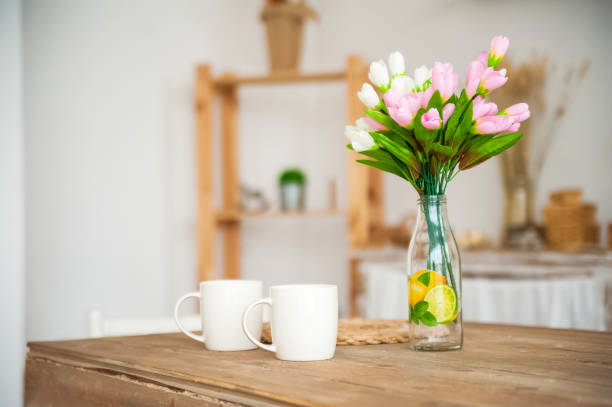 istock Breakfast cups and fruit. Spring tulips on the table. Wooden table in a bright rustic-style kitchen. Scandinavian style in the interior of the kitchen. 1153450662