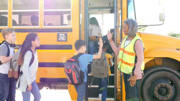 istock Bus driver greets children boarding bus 1153451738