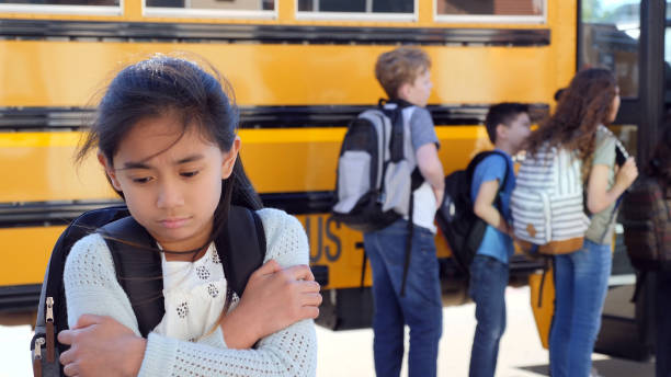 Preteen girl excluded from group struggles with loneliness A female junior high school student looks down sadly as she struggles with loneliness after having been excluded from a group of friends. school exclusion stock pictures, royalty-free photos & images