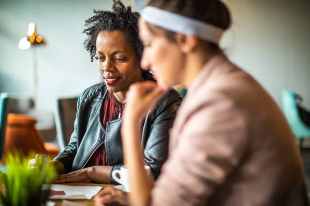 istock Multi-ethnic female friends using phone in cafe 1153453400