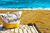 image of a beach bag on top of a towel overlooking the sea and sunbeams on which to put hello summer.
