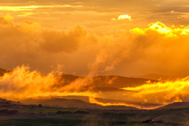 istock Colourful sunset over a rolling landscape with low clouds 1153454539