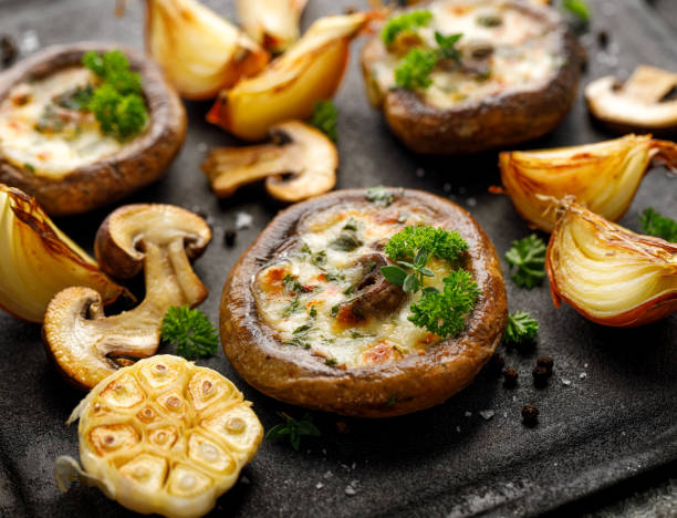 funghi portobello arrostiti ripieni di formaggio ed erbe su fondo di ferro nero, primo piano. - edible mushroom stuffed portabello mushroom vegetarian food foto e immagini stock