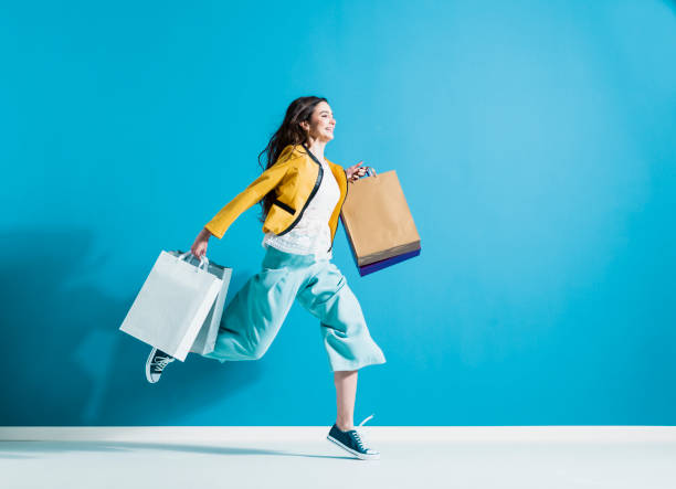 Cheerful happy woman enjoying shopping Cheerful happy woman enjoying shopping: she is carrying shopping bags and running to get the latest offers at the shopping center fashionable shopping stock pictures, royalty-free photos & images