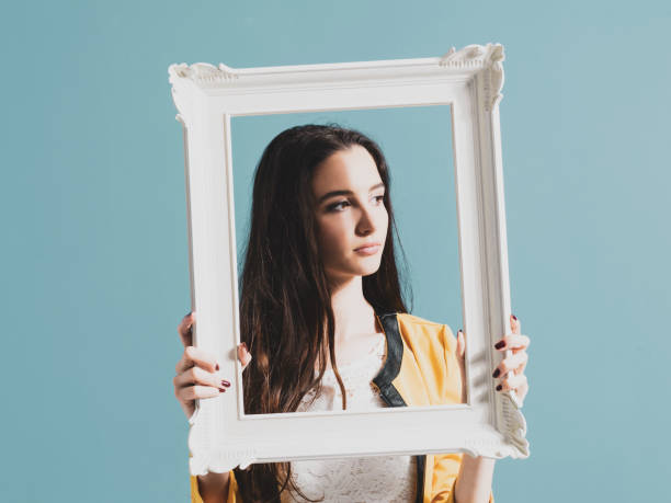 istock Beautiful woman posing and holding a frame 1153458626