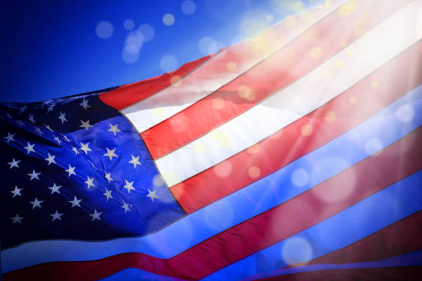istock close up waving American flag and light beam with abstract lights 1153458655