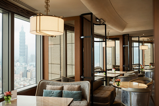 Empty chairs and tables in restaurant. Pendant light is hanging over furniture. Interior of hotel.