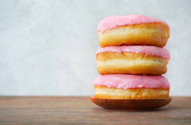istock Stack of three strawberry cream donuts on wood table and gray background. 1153460852