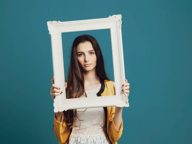 istock Beautiful woman posing and holding a frame 1153461921