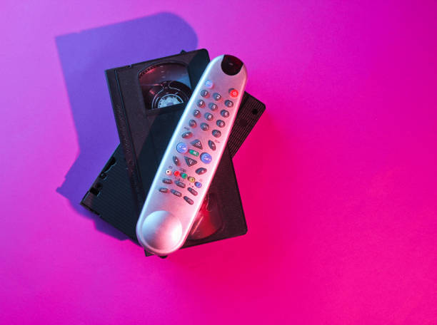 istock Retro wave style tv remote and  video cassette with neon pink-blue light. 80s. Top view 1153462162