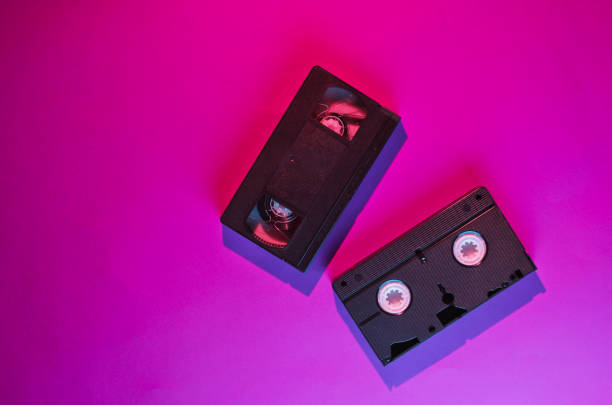 istock Retro wave style two video cassette with neon pink-blue light. 80s. Top view 1153462170