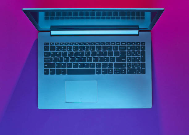 istock Modern laptop with vibrant gradient pink blue neon  lights. Minimalism. Top view 1153463170