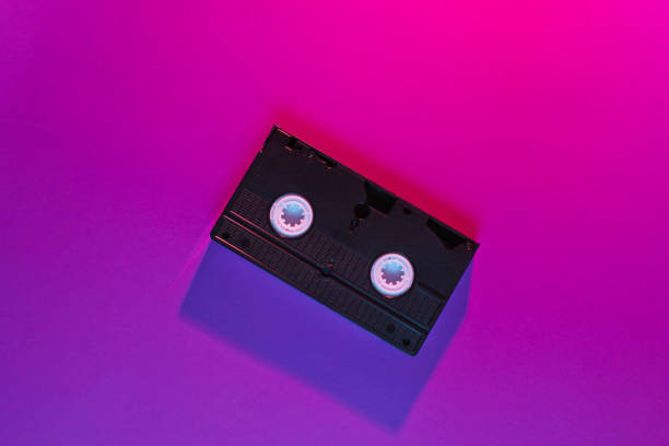 istock Retro wave style video cassette with neon pink-violet light. 80s. Top view 1153463263