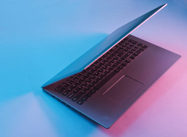 istock Modern laptop with vibrant gradient pink blue neon  lights. Minimal office surrealism concept. 1153463414