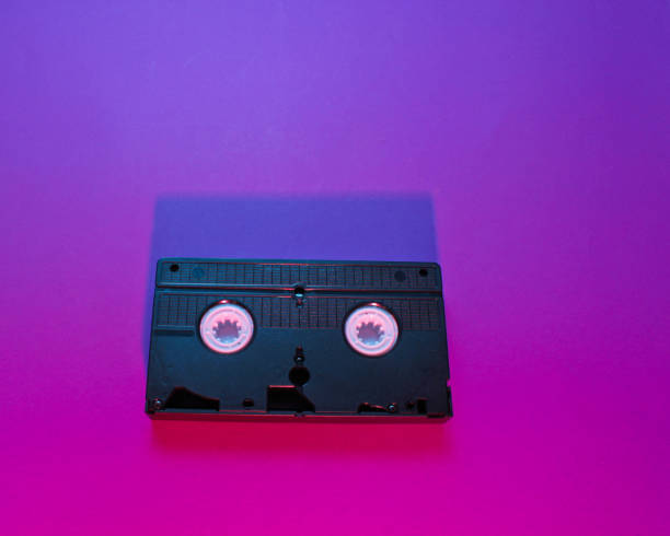 istock Retro wave style video cassette with neon pink-violet light. 80s. Top view 1153463534