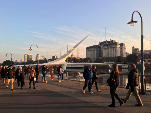 People enjoying sunset at Puerto Madero, Buenos Aires, Argentina Buenos Aires, Argentina - June 2, 2019: People enjoying sunday evening walking through promenade at Puerto Madero neighborhood. This place is well known for its food offers and open spaces to enjoy for a city break puente de la mujer stock pictures, royalty-free photos & images