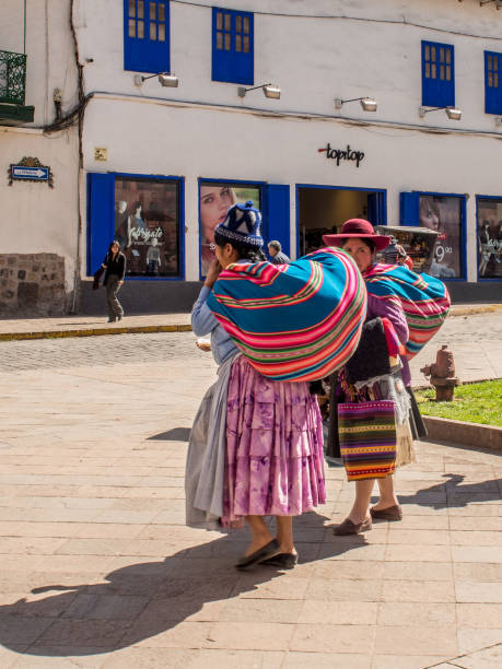 Peru, Cusco-March 14,2025: Indigenous locals in traditional Andean clothing walk through the historic streets of Cusco, reflecting the rich cultural heritage of the Peruvian Andes