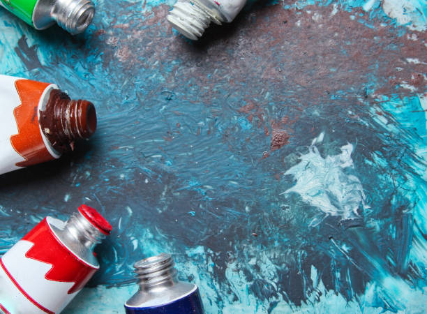 istock Tubes of paint on a blue painted background 1153466678
