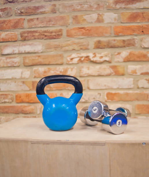 istock Functional training concept. Kettlebell, dumbbell stand on wooden box against the brick wall background. Workout equipment 1153468055