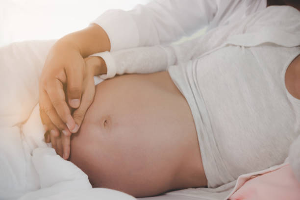 husband or father holding his wife or pregnant woman hand together with love on cozy bed at bedroom. couple feel happiness because they get first child. pregnant woman is pregnant for eight months - baby lying down sleeping asian ethnicity imagens e fotografias de stock