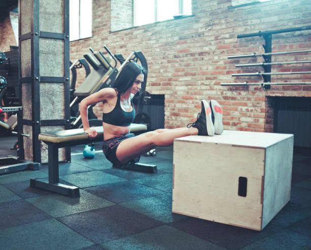 istock Young brunette in sportswear doing rear push ups for triceps from bench. Training with your weight in the gym 1153469539