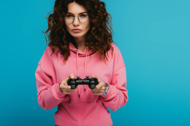 istock serious curly redhead girl playing video game while holding joystick on blue 1153469990