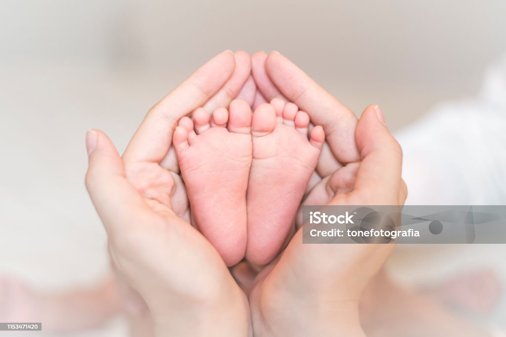 Close up of newborn baby feet on female hands Baby - Human Age Stock Photo