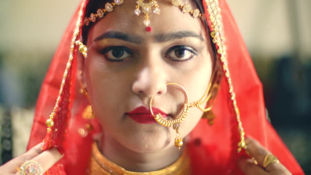 Beautiful Hindu bride in traditional dress looks at the camera.