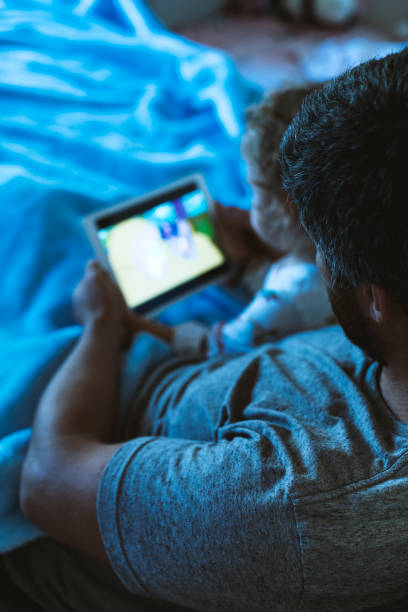 istock Toddler girl watching tablet in bed with her dad 1153472676