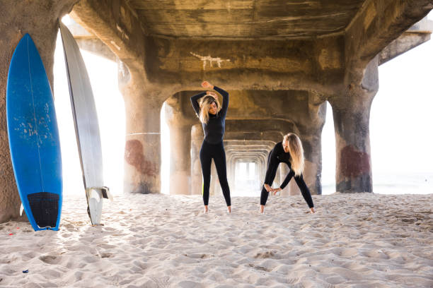 女性の友人はサーフィンに行く - santa monica surfing beach city of los angeles ストックフォトと画像