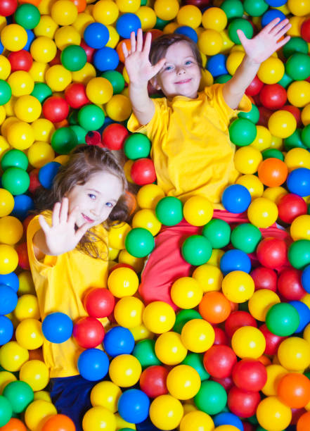 istock Two Happy little girls playing and having fun at kindergarten with colorful balls in play center 1153473228