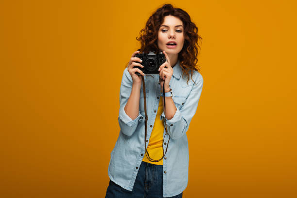 istock attractive redhead photographer holding digital camera on orange 1153476231