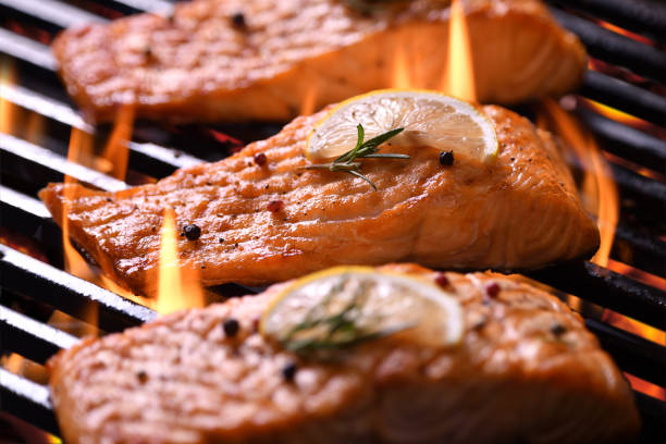 istock Grilled salmon fish with various vegetables on the flaming grill 1153477251