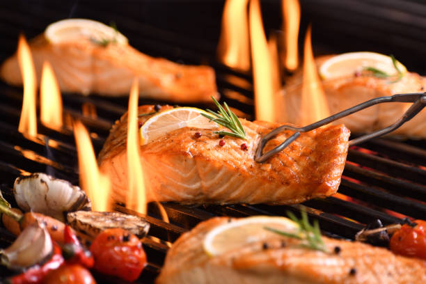 istock Grilled salmon fish with various vegetables on the flaming grill 1153477253