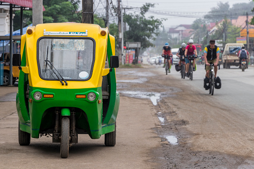 Eco-friendly electronic tuk tuk in Luang Prabang, Laos. Green and yellow vehicle. Car rickshaw in Asia.
